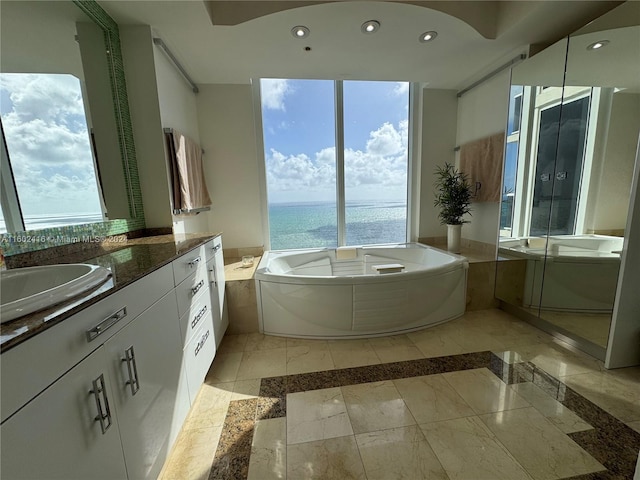 bathroom with recessed lighting, a healthy amount of sunlight, a garden tub, and vanity