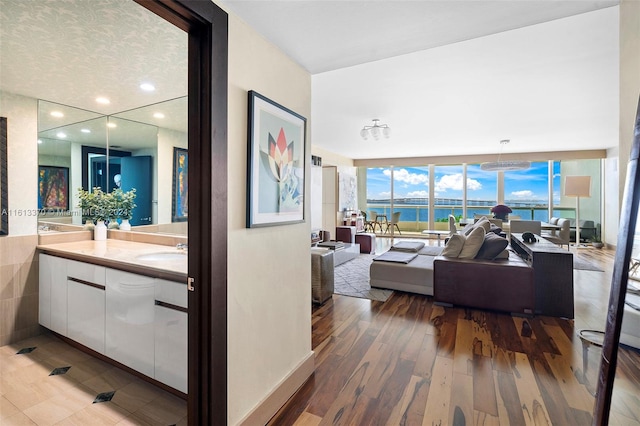 living room with a water view, hardwood / wood-style flooring, sink, and a wall of windows