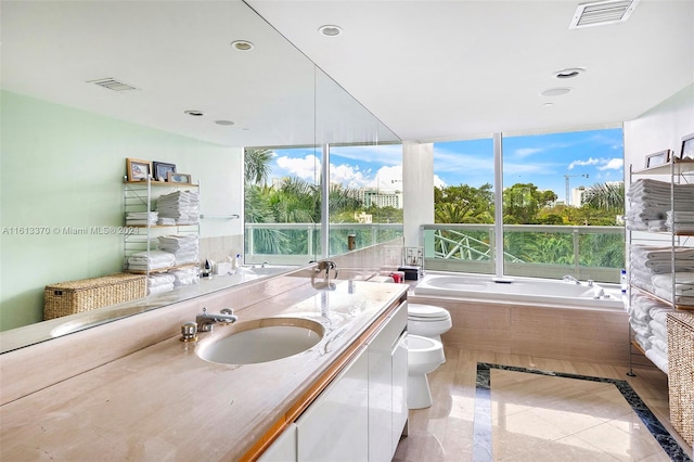 bathroom featuring toilet, a tub to relax in, vanity, and a bidet