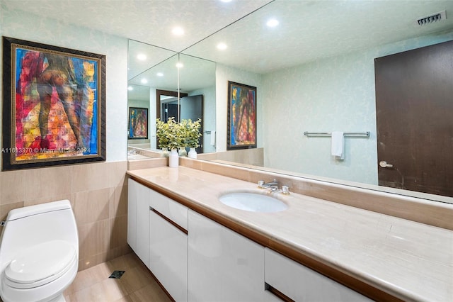 bathroom with vanity, toilet, tile patterned floors, and tile walls