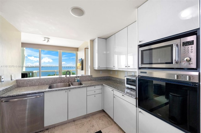 kitchen featuring sink, appliances with stainless steel finishes, a water view, and white cabinets