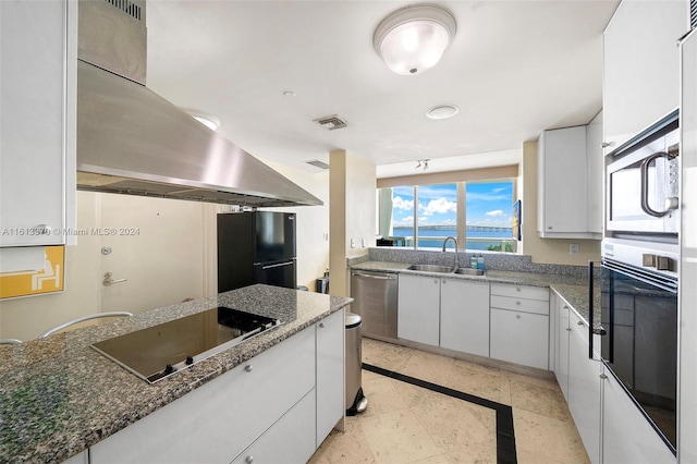 kitchen with dark stone countertops, sink, black appliances, white cabinetry, and a water view