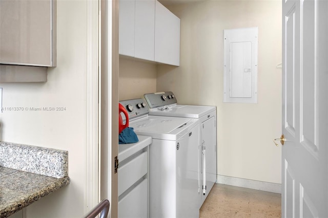 laundry area with electric panel, cabinets, and washer and clothes dryer