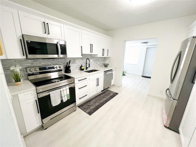 kitchen with sink, white cabinetry, tasteful backsplash, light hardwood / wood-style flooring, and stainless steel appliances