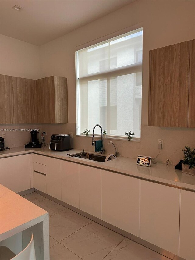 kitchen with white cabinets, sink, tasteful backsplash, and light tile floors