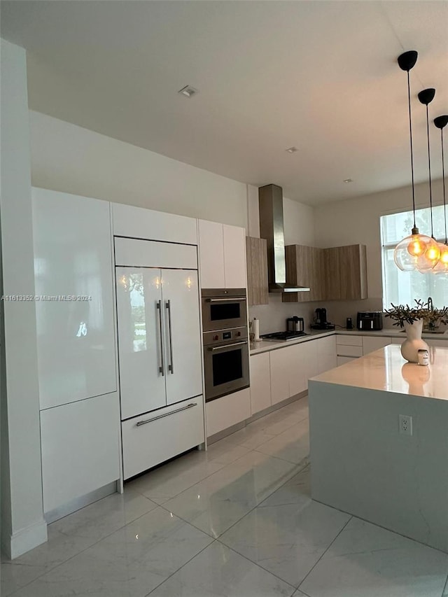 kitchen with paneled fridge, decorative light fixtures, light tile floors, wall chimney range hood, and double oven