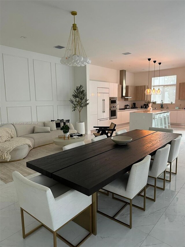 dining space featuring a notable chandelier, sink, and light tile floors