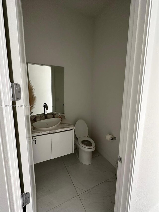 bathroom featuring tile flooring, vanity, and toilet