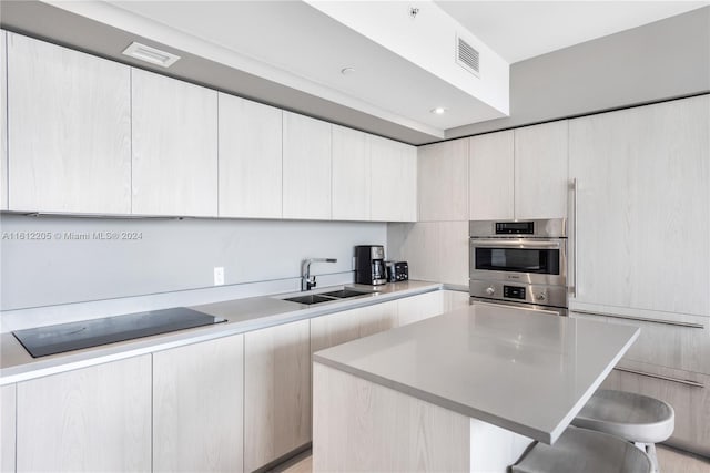 kitchen featuring a center island, a kitchen breakfast bar, stainless steel double oven, white cabinets, and sink