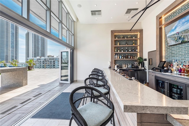 bar with light stone countertops, backsplash, wine cooler, and light tile floors