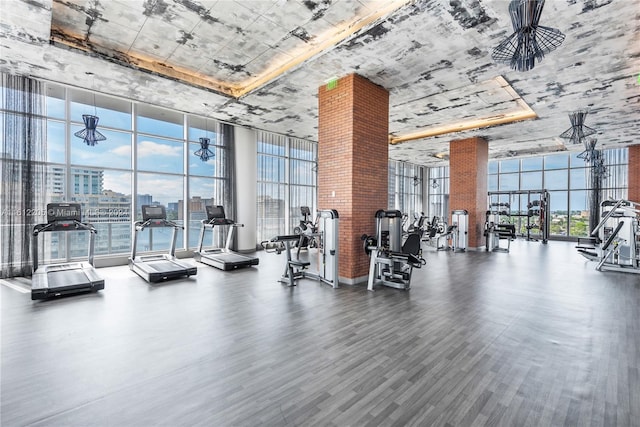 workout area featuring floor to ceiling windows, brick wall, and dark hardwood / wood-style flooring