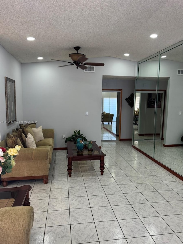 living room featuring ceiling fan, a textured ceiling, and light tile patterned flooring