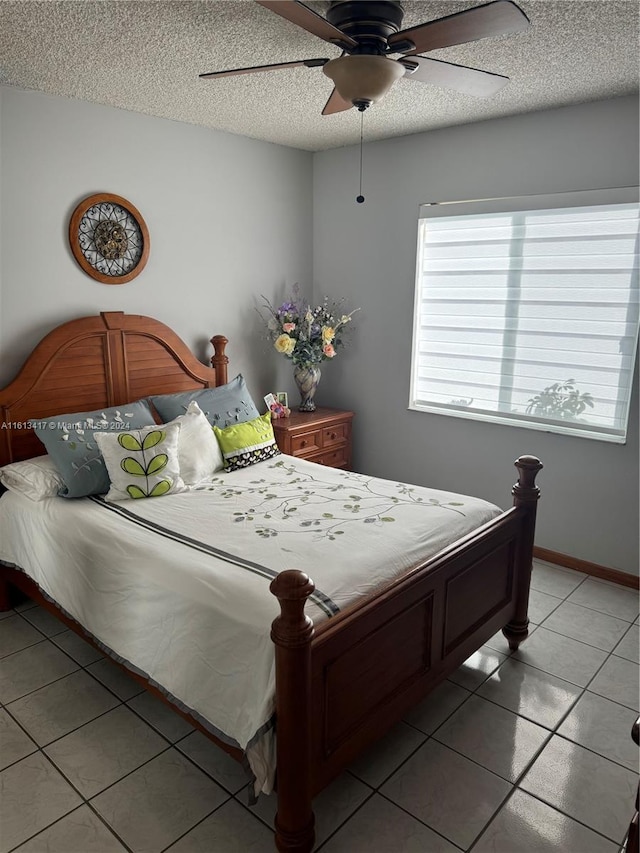 bedroom with a textured ceiling, light tile patterned flooring, and ceiling fan