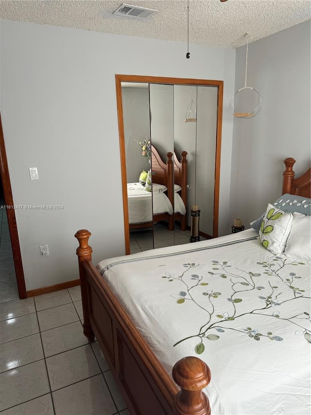 bedroom with light tile patterned flooring, a textured ceiling, and a closet