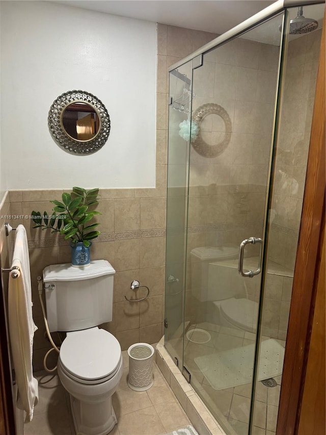 bathroom with toilet, a shower with shower door, tile patterned floors, and tile walls