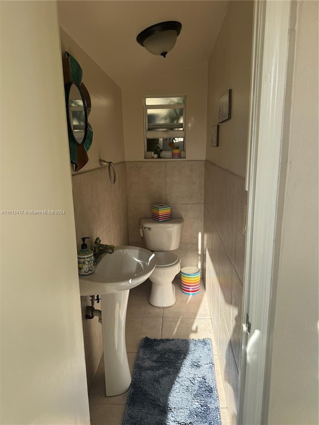 bathroom featuring toilet, tile patterned floors, tile walls, and lofted ceiling