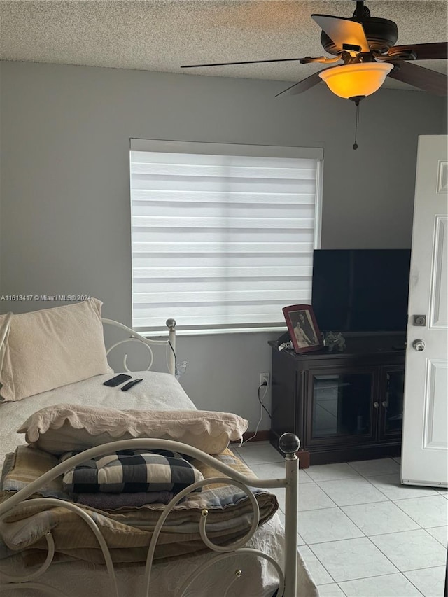 bedroom featuring a textured ceiling, light tile patterned floors, and ceiling fan