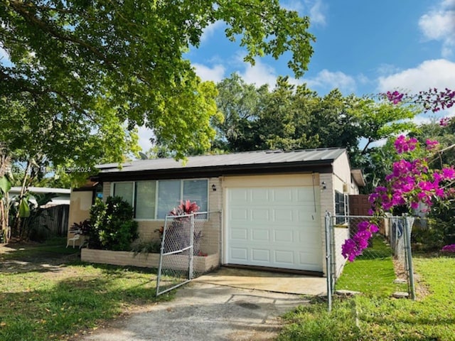 view of front facade with driveway, an attached garage, fence, and metal roof