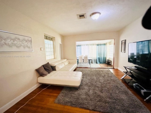 living room featuring a wealth of natural light, baseboards, visible vents, and dark wood-type flooring