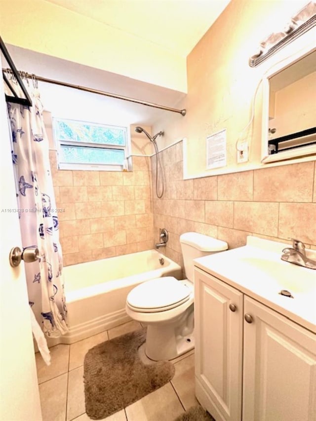 full bathroom with tile floors, shower / bath combo with shower curtain, tile walls, and vanity