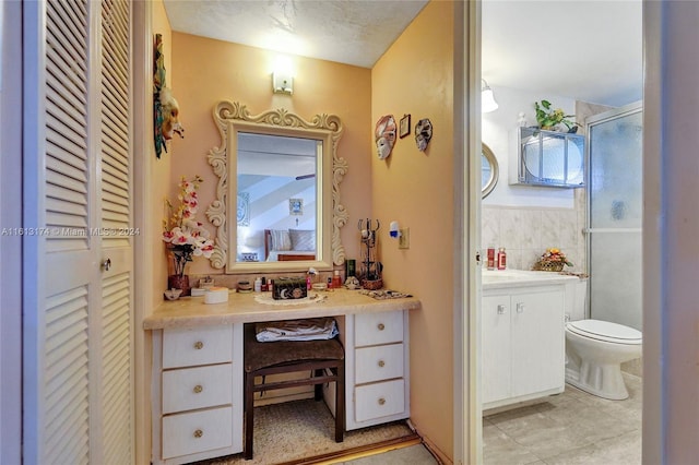 full bath with a shower stall, tile walls, toilet, a closet, and vanity