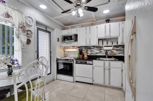 kitchen featuring dark countertops, light tile patterned flooring, white cabinets, white appliances, and a sink