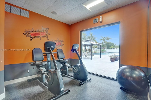 exercise room featuring a drop ceiling and baseboards