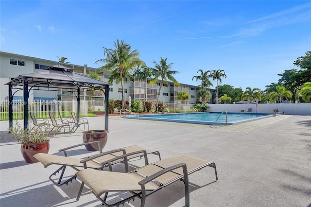 community pool with a gazebo, fence, and a patio