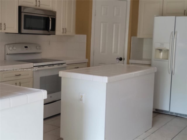 kitchen with white appliances, decorative backsplash, a center island, and tile counters