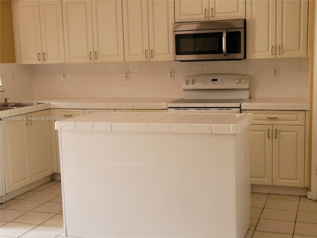 kitchen with light tile patterned flooring, a center island, white range oven, and tile counters