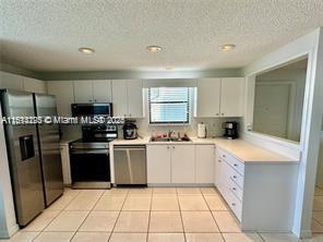 kitchen featuring sink, white cabinets, light tile patterned flooring, and appliances with stainless steel finishes