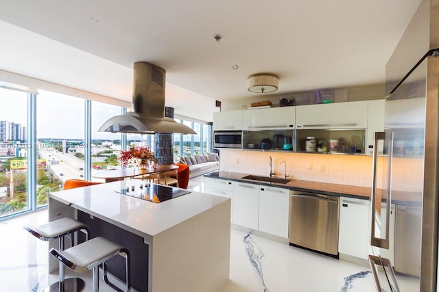 kitchen featuring sink, white cabinetry, island exhaust hood, and appliances with stainless steel finishes