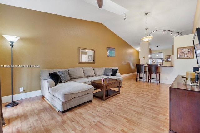 living room featuring sink, track lighting, wood-type flooring, and lofted ceiling