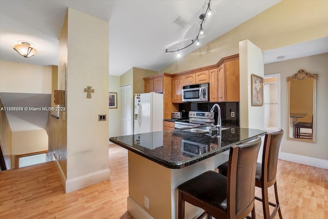 kitchen with track lighting, appliances with stainless steel finishes, light hardwood / wood-style flooring, and tasteful backsplash