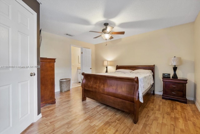 bedroom with a textured ceiling, ceiling fan, ensuite bath, and light hardwood / wood-style flooring