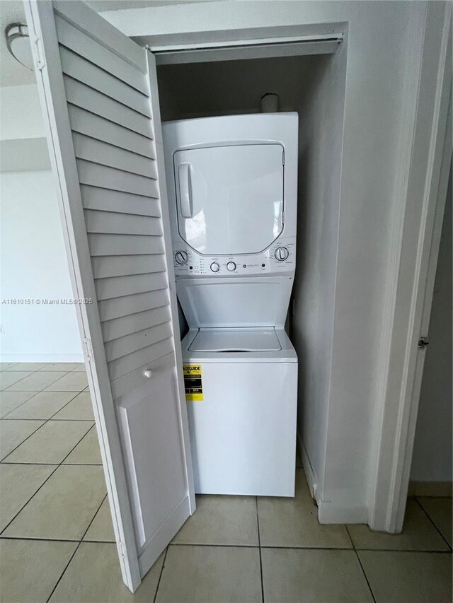 laundry room featuring stacked washer and dryer and light tile patterned floors