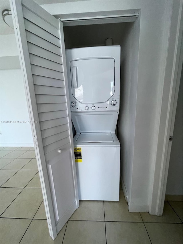 laundry room featuring stacked washer / drying machine and light tile patterned floors