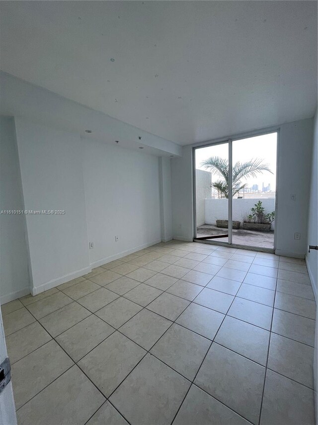 tiled spare room featuring a wall of windows