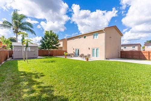 rear view of property featuring a patio, a shed, and a lawn