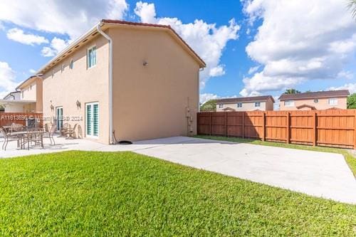 back of house featuring a lawn and a patio area