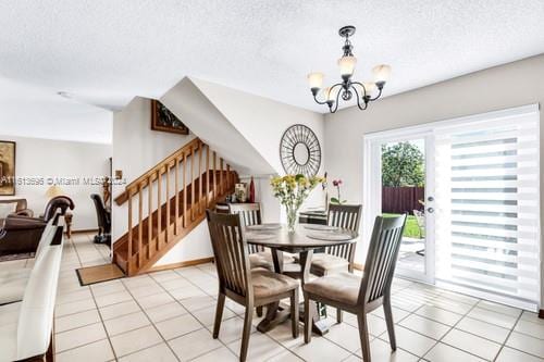 tiled dining area with a chandelier and a textured ceiling