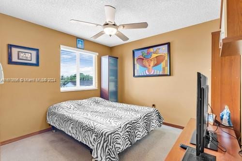 bedroom with ceiling fan, carpet floors, and a textured ceiling