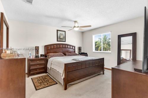 carpeted bedroom featuring a textured ceiling and ceiling fan