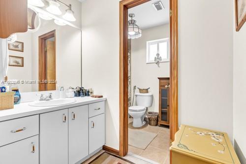 bathroom with tile floors, vanity with extensive cabinet space, and toilet