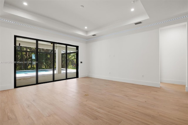 empty room featuring a raised ceiling and light wood-type flooring