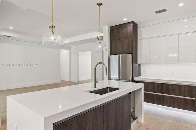 kitchen with pendant lighting, white cabinets, sink, stainless steel fridge, and dark brown cabinets