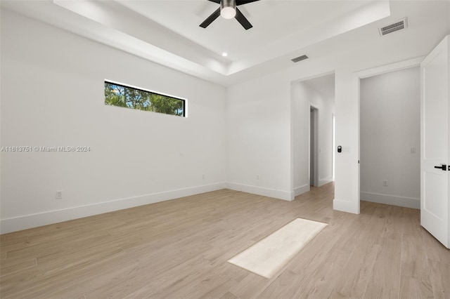 unfurnished bedroom featuring a tray ceiling, ceiling fan, and light hardwood / wood-style flooring