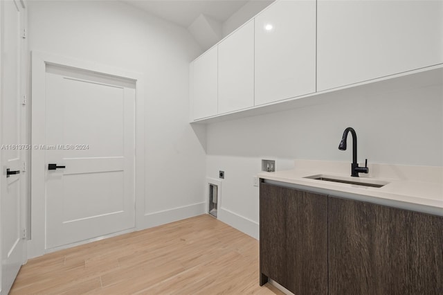 clothes washing area with electric dryer hookup, cabinets, sink, hookup for a washing machine, and light hardwood / wood-style flooring