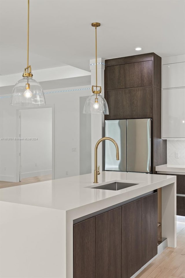 kitchen with stainless steel fridge, light hardwood / wood-style flooring, dark brown cabinets, and sink