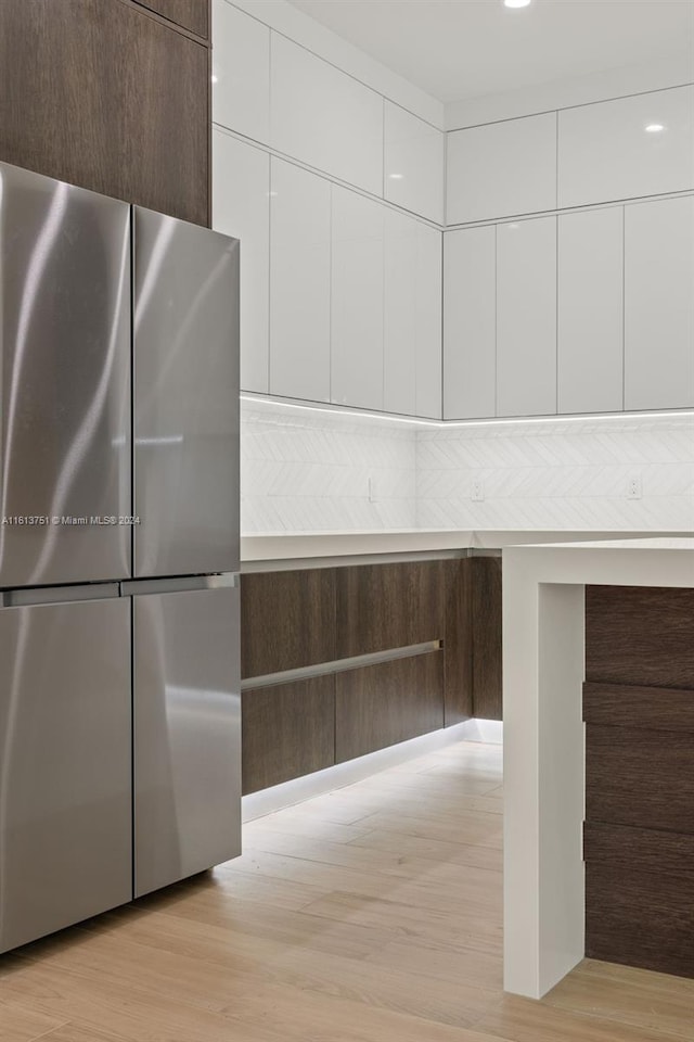 kitchen with white cabinets, stainless steel fridge, and light hardwood / wood-style floors